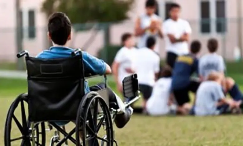صورة لطفل من ذوي الإعاقة الحركية ينظر من بعيد لآخرين أثناء العب